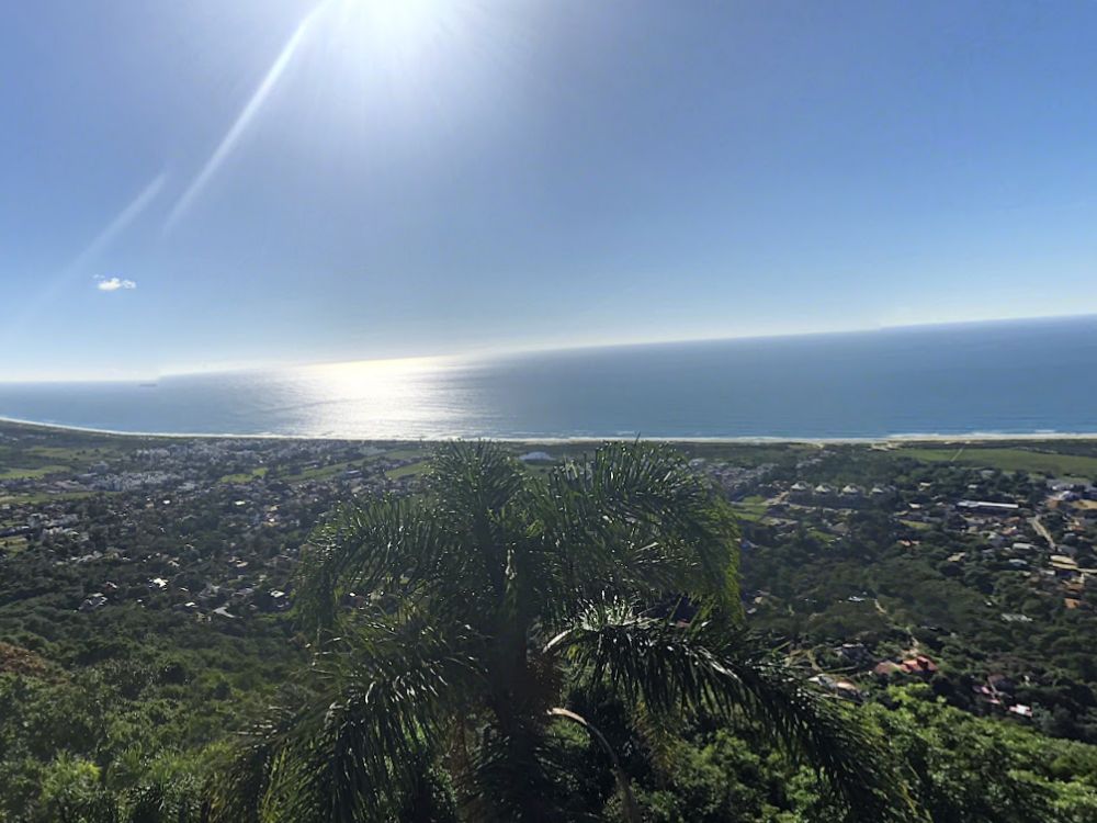 Vista panorâmica do Bairro Campeche Florianópolis a partir de mirante, com área urbana cercada por mata nativa e faixa litorânea preservada.