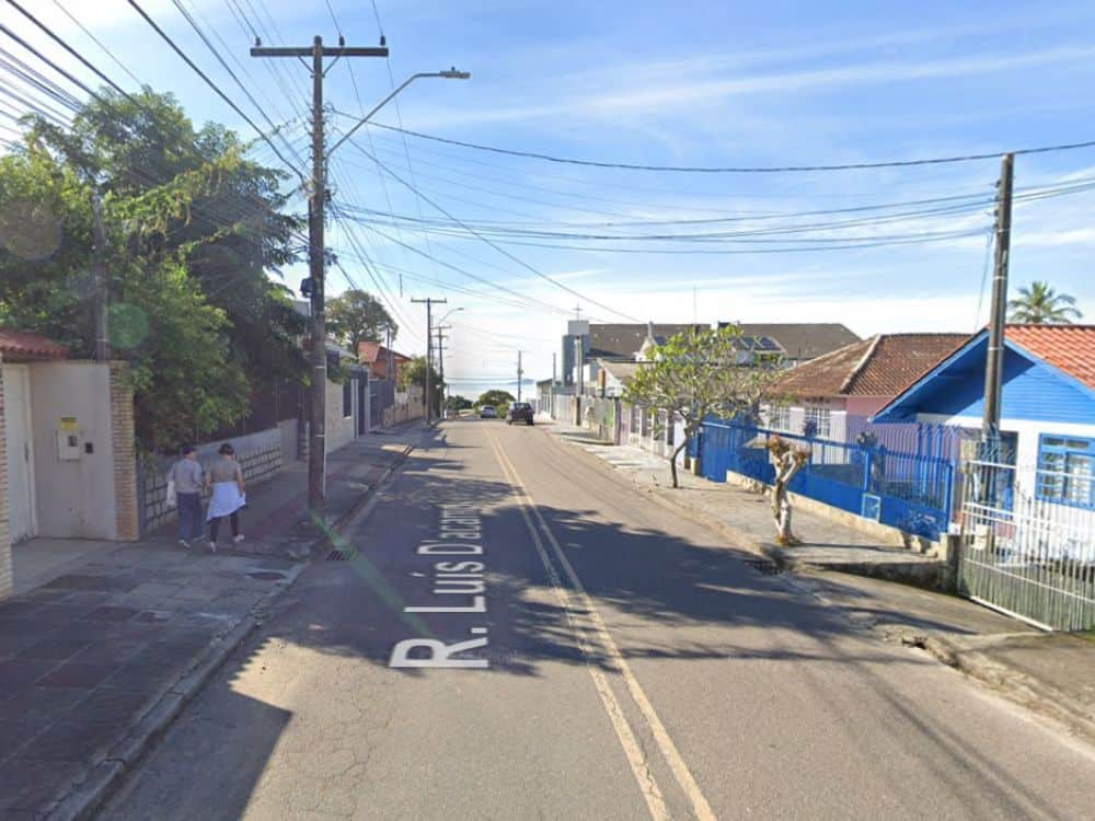 Moradores caminhando por rua arborizada destacam o clima acolhedor e familiar do bairro Jardim Atlântico SC em Florianópolis.