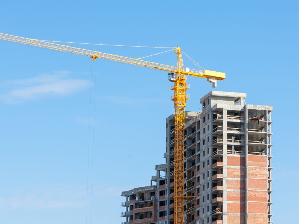 Edifício alto em fase de alvenaria estrutural com guindaste, simbolizando a execução sob demanda do modelo BTS.