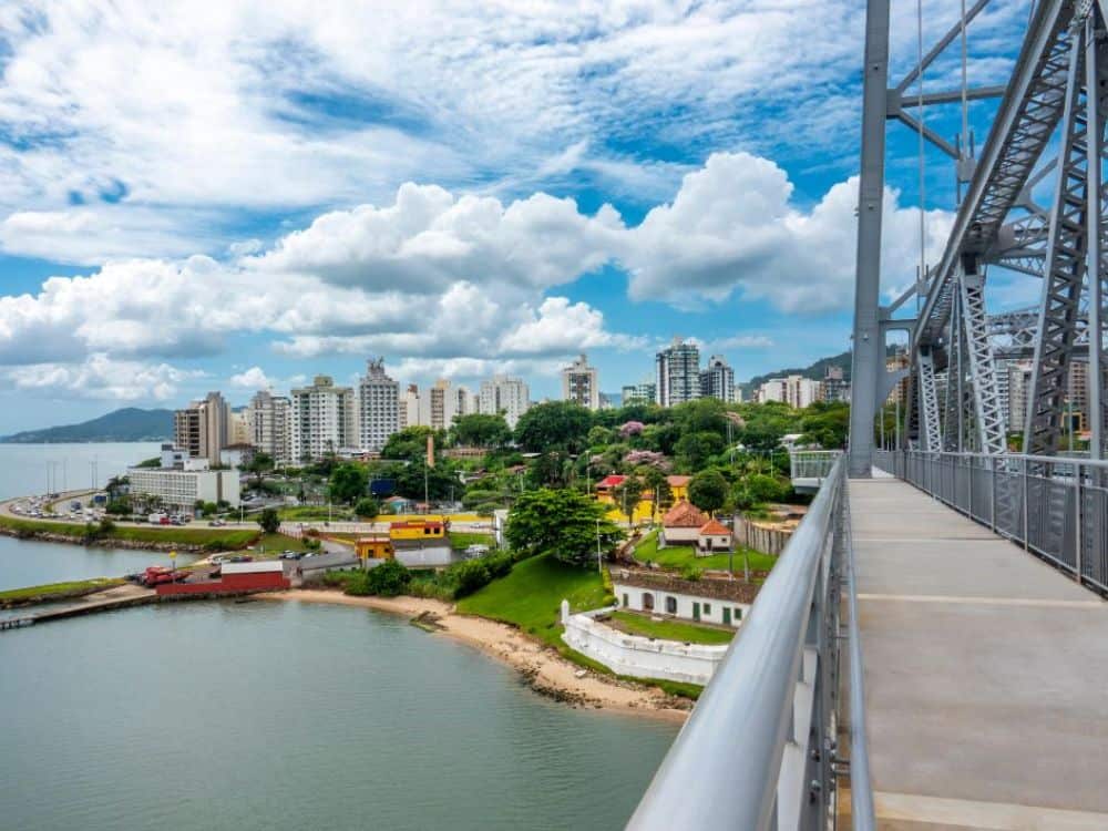 Ponte ligando diferentes áreas da cidade de Florianópolis, com prédios modernos e paisagem verde ao redor, refletindo a infraestrutura da cidade. Sim, florianópolis é seguro!