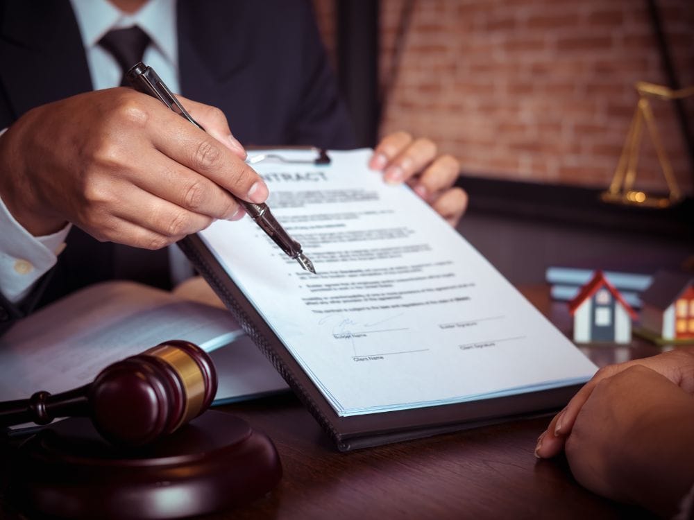 Pessoa de terno segurando caneta e mostrando cláusulas de contrato relacionadas à rescisão de aluguel.