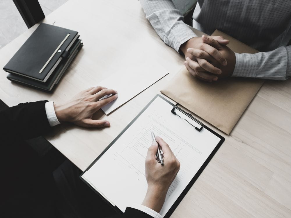 Duas pessoas sentadas à mesa analisando documentos e contrato em processo de rescisão de aluguel.