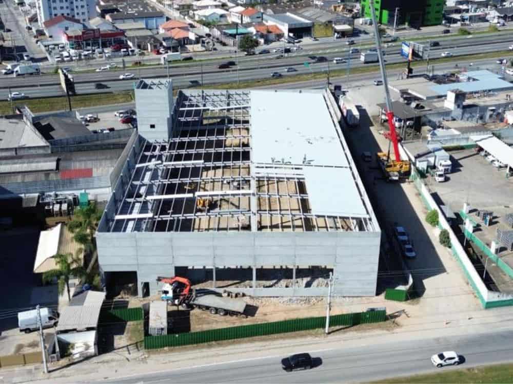 Imagem aérea mostra construção de galpão comercial em fase estrutural, ilustrando um projeto corporativo sob medida típico de Built to Suit exemplos modernos.