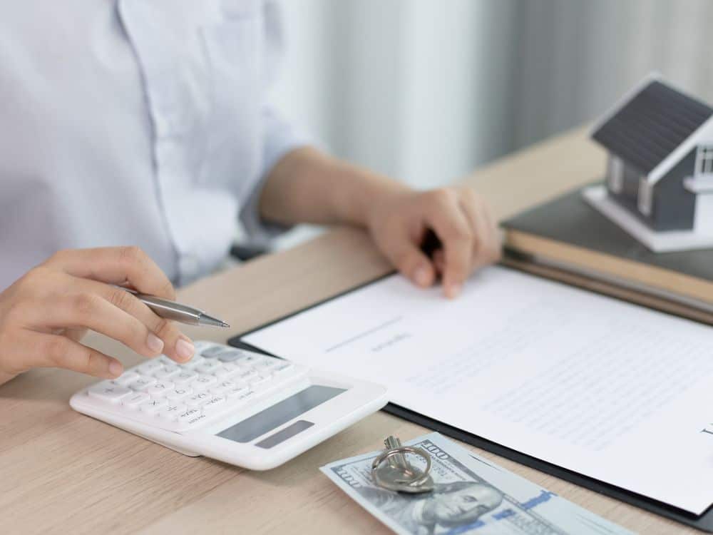 Mãos calculando valores e revisando contrato imobiliário, exemplo visual de Como calcular reajuste de aluguel com transparência e precisão.