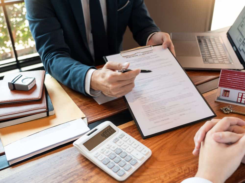 Cena corporativa com corretor explicando planilhas e contrato, demonstrando Como calcular reajuste de aluguel segundo os índices oficiais.