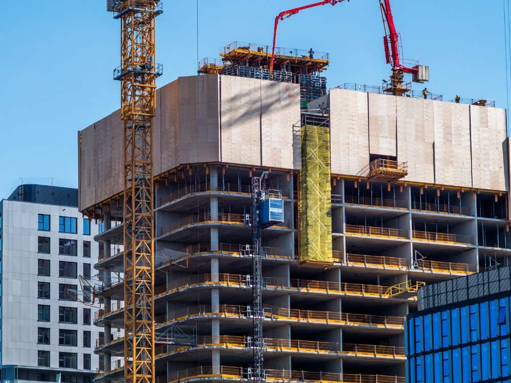 Prédio em construção com gruas e operários, retratando grandes empreendimentos presentes nos Built to Suit exemplos de sucesso empresarial.