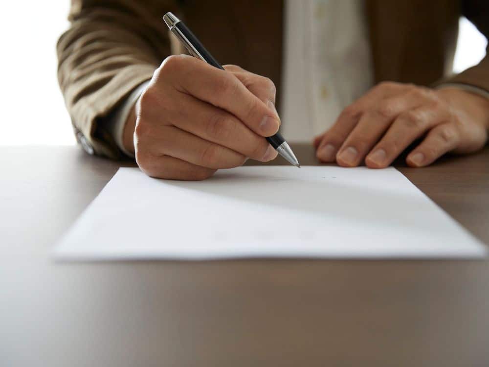 Pessoa assinando documento relacionado ao direito de preferência do locatário em caso de venda do imóvel.