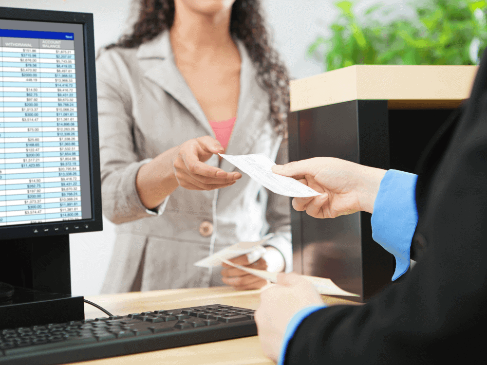 Cliente recebe documentos em atendimento bancário para dar continuidade ao financiamento de imóvel usado e à análise de crédito.