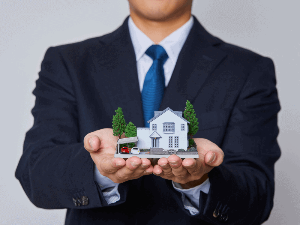 Profissional segurando uma maquete de casa nas mãos, representando investimento e oportunidades de valorização no mercado imobiliário.